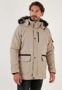 Bežīgs pufīgs mētelis ar noņemamu mākslīgo kažokādu, melniem akcentiem, ar rāvējslēdzēja krūšu kabatu un divām priekšējām kabatām. Tekstūrēta auduma.