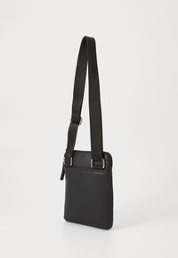 Black leather crossbody bag with a flat design, adjustable fabric strap, and zip closure. Features silver-tone hardware and a smooth texture.