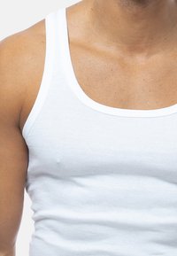 White cotton tank top with wide shoulder straps, featuring a round neckline and a smooth texture. No notable patterns or accents.