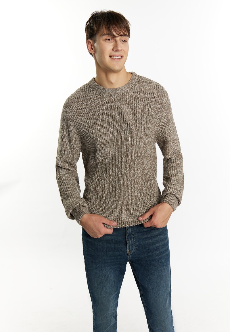 Pulover tricotat cu un model bej și maro melanj, decolteu rotund, textură ribbed și mâneci lungi. Asortat cu blugi din denim albastru.