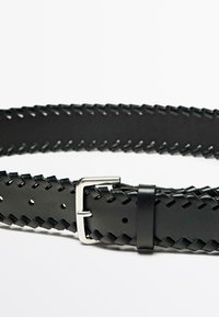 Zwarte gevlochten leren riem met een zilveren metalen gesp en gestikte details, voorzien van gaatjes langs de lengte voor verstelbaarheid.