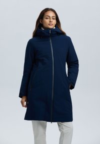 Marineblauwe waterdichte jas met hoge kraag, ritssluiting aan de voorkant en zijzakken. Beschikt over een soepele textuur en een verstelbare capuchon voor extra warmte.