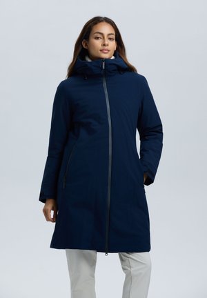 Marineblauwe waterdichte jas met hoge kraag, ritssluiting aan de voorkant en zijzakken. Beschikt over een soepele textuur en een verstelbare capuchon voor extra warmte.