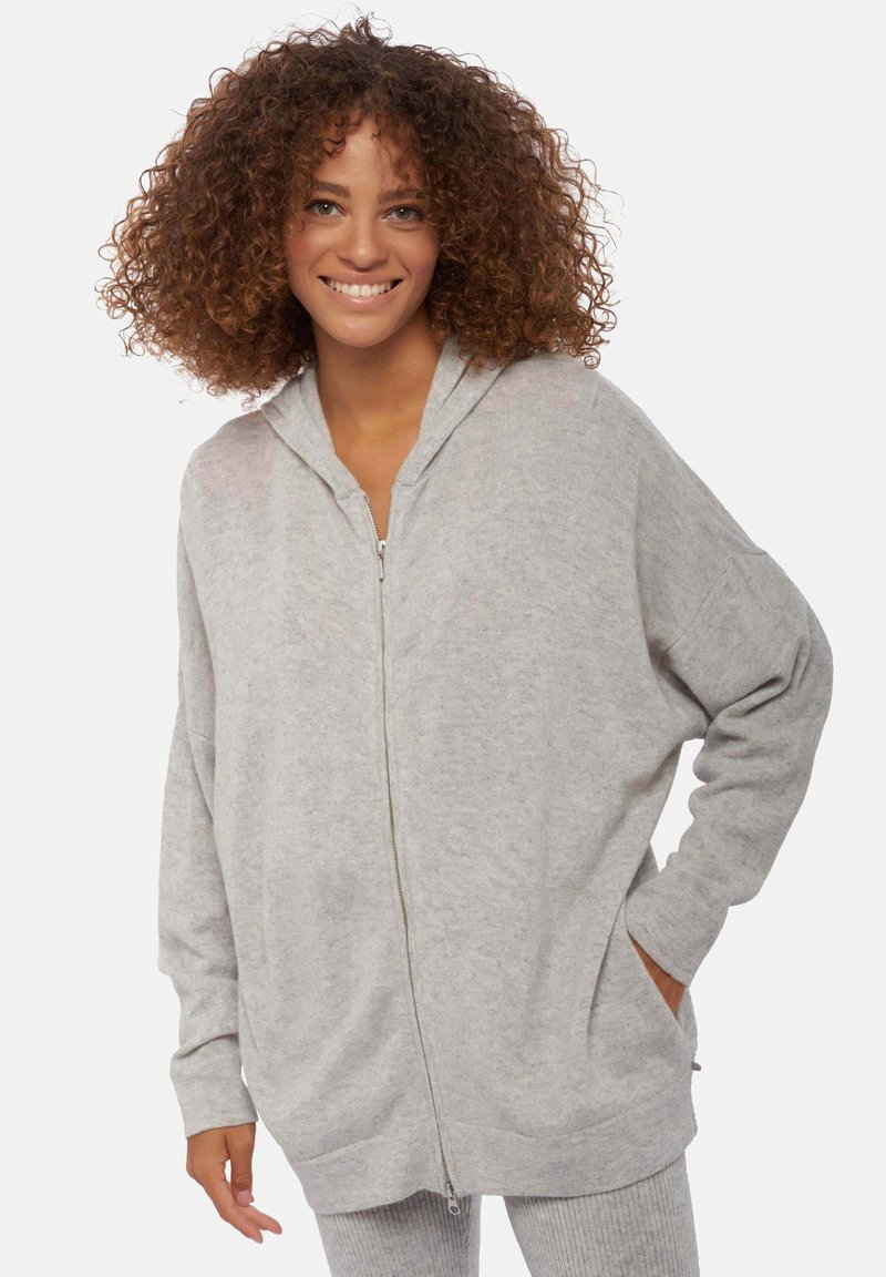 Sweat à capuche gris clair avec fermeture éclair, coupe décontractée, manches longues, capuche à cordon et poches latérales. Tissu doux et texturé.