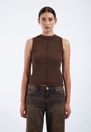 Bruine geribbelde tanktop met een hoge halslijn en een naaddetails aan de voorkant, gecombineerd met losse, donkerbruine spijkerbroeken.