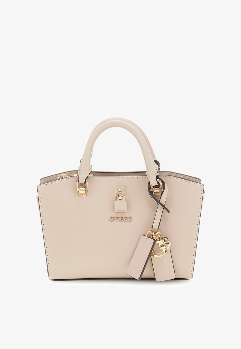 Sac à main synthétique beige avec une forme structurée, deux poignées, quincaillerie dorée et un logo. Comprend des étiquettes décoratives et des accents.