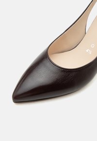 Σκούρο καφέ δερμάτινο παπούτσι slingback με μυτερή μύτη και χαμηλό τακούνι, μπεζ εσωτερική επένδυση, μέγεθος 4½ ορατό στο εσωτερικό.