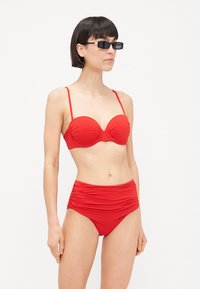 Rød bikini sæt med en polstret, struktureret top og højtaljede bund med samlede stofteksturer. Enkle justerbare stropper og ingen mønstre.