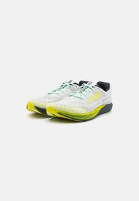 Chaussures de course légères avec une tige en maille blanche, des lacets verts, une semelle jaune et grise, et un design épuré pour la performance.