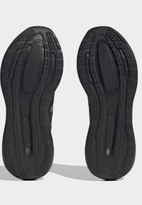 Czarne sportowe podeszwy butów wykonane są z teksturowanej gumy o wzorzystej powierzchni, zapewniającej przyczepność. Logo widoczne jest po bokach każdej podeszwy.