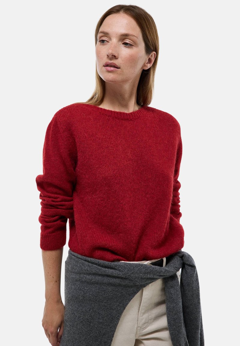 Sweater en tricot rouge avec un col rond et des manches longues, associé à un châle en tricot gris noué autour de la taille. Design simple, texture douce.