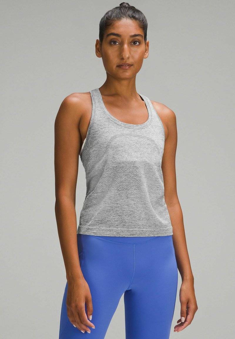 Gray athletic tank top with a textured finish, featuring a round neckline and wide shoulder straps, paired with blue fitted leggings.
