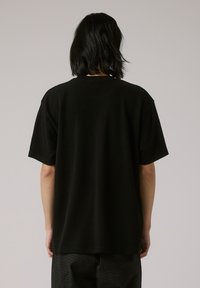 Black short-sleeve T-shirt made of soft fabric, featuring a relaxed fit and a simple, unembellished design. Smooth texture.