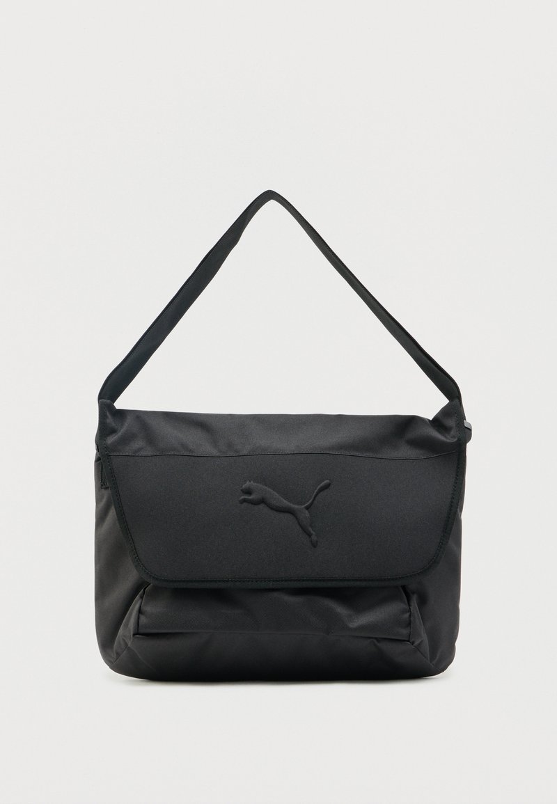 Μαύρη τσάντα ώμου με καπάκι που κλείνει, με ανάγλυφο λογότυπο Puma, φαρδιά ρυθμιζόμενη ράβδο, και μπροστινή τσέπη με φερμουάρ.