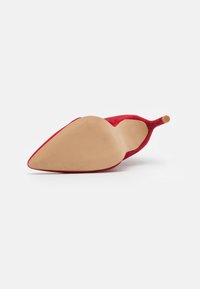 Escarpin en suédine rouge avec un bout pointu. Semelle extérieure en caoutchouc beige lisse avec un motif de grip texturé. Structure de talon fine avec une pointe arrondie.