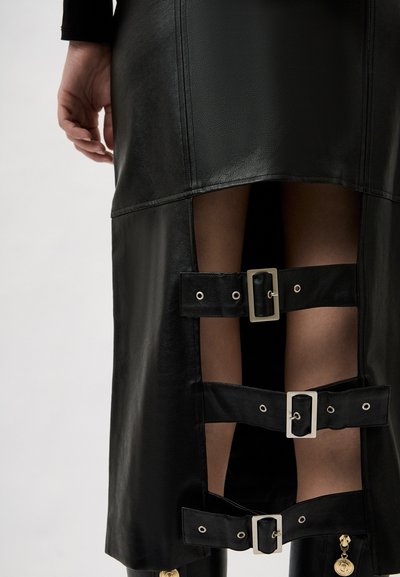 Black leather skirt with a fitted design, featuring cut-out details and three buckle straps with silver hardware along the slits.