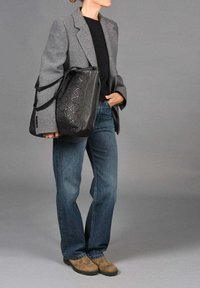 Grijze wollen blazer over een zwarte top, gecombineerd met blauwe jeans en bruine suède laarzen. Draagt een grote zwarte leren tas met geweven textuur.