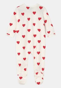 Røde hjerte mønstre på en kremfarget baby onesie med lange ermer, føtter og rund halslinning. Myk, elastisk stoff.