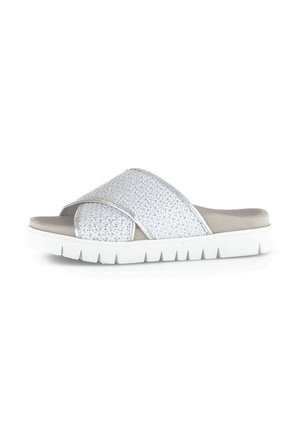 White slide sandals feature crisscross woven upper, soft beige footbed, and a thick white outsole with a ridged pattern for traction.