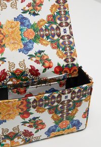 Barevný květinový potisk na syntetickém materiálu, obdélníkový design s vzorovanou texturou. Obsahuje více přihrádek a pevný okraj.