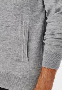 Szara bluza z kieszenią boczną, ściągaczami przy rękawach i u dołu. Tekstura wydaje się gładka z miękkim, przytulnym wykończeniem.