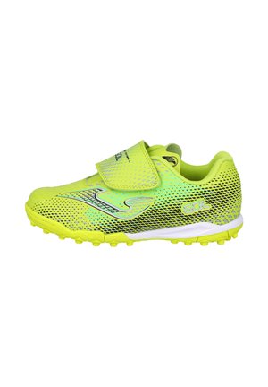 Taco de color verde amarillento brillante con patrón de puntos negros, cierre de velcro y suela texturizada diseñada para césped artificial o turf.
