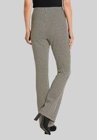 Aansluitende, high-waisted broek in een zwart-wit houndstoothpatroon, met een gladde textuur en een uitlopende pijpdesign.