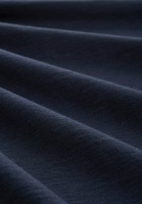 Tejido de color marino con una textura suave, que presenta pliegues suaves y un ligero brillo, capturando la interacción de la luz en su superficie.