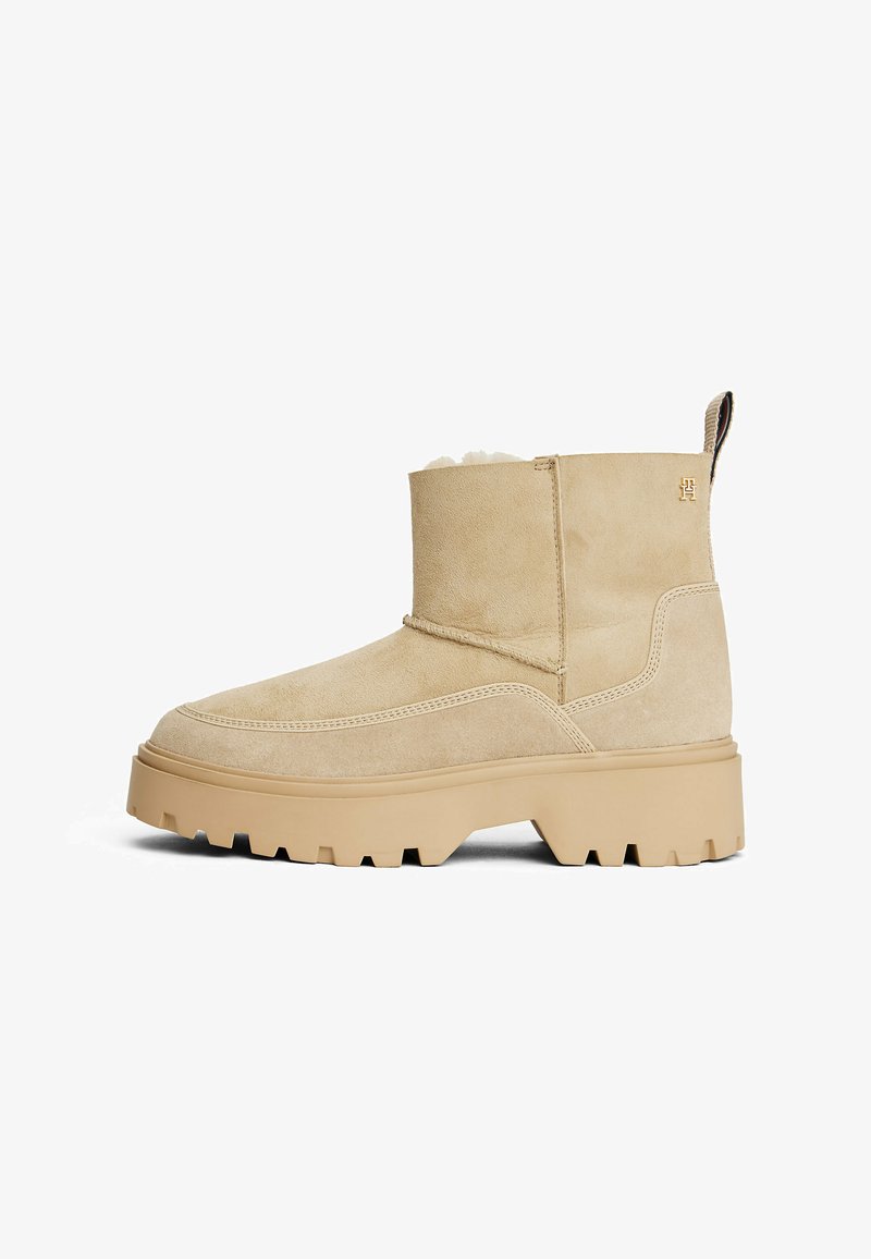 Beige suède enkellaars met een chunkyy, gestructureerde rubberen zool, met een ronde neus en gestikte details, voorzien van een klein logoaccent.