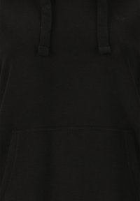 Musta huppari, jossa on narut ja etupuolella kengurulaukku, jossa on pieni, huomaamaton brodeerattu logo rinnassa.