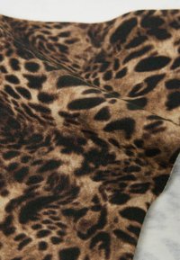Leopardprint stof met bruine en zwarte vlekken op een beige achtergrond; gladde textuur met een lichte glans.