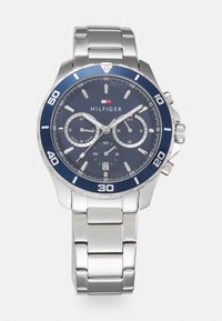 Montre en acier inoxydable argenté avec un cadran bleu, des sous-cadrans chronographe et un affichage de la date. Dotée d'indicateurs d'heure blancs audacieux et d'une lunette bleue.