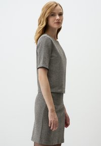 Robe à motif pied-de-poule gris avec des manches courtes, présentant une coupe structurée et un tissu texturé, atteignant la longueur mi-thigh.