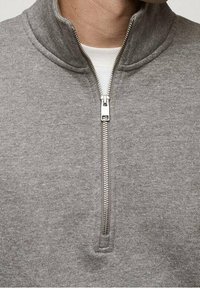 Sudadera gris con diseño de media cremallera, fabricada con tela suave. Presenta un cuello alto y una cremallera lisa con herrajes de metal.