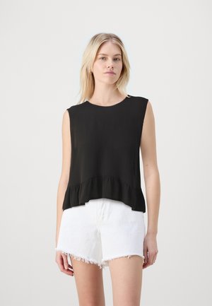 Black sleeveless top with a textured finish and ruffled hem, paired with white distressed shorts, presented against a neutral background.