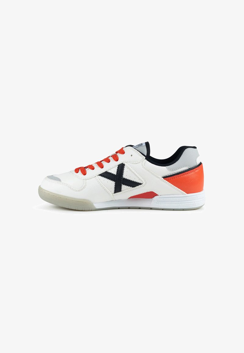 Baskets blanches avec lacets rouges, logo X noir sur le côté, patch rouge au talon et semelle translucide, vues de l'extérieur.