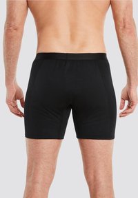 Schwarze Boxershorts aus glattem, dehnbarem Stoff. Mit breitem Bund und körpernahem Design, mit sichtbaren Nahtdetails.