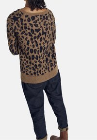 Beige tröja med svart leopardmönster, rund halsringning och ribbad nederkant. Matchad med mörka jeans, uppvikta nederkanter och bruna stövlar.
