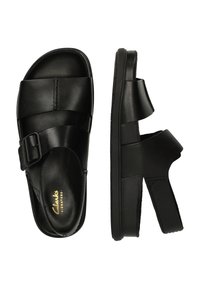 Czarne skórzane sandały z krzyżowym paskiem i regulowanym zapięciem. Gruba, teksturowana podeszwa zapewniająca lepszą przyczepność i komfort.