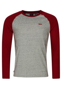 Långärmad raglantröja med hängande grå kropp och mörkröda ärmar, med en liten röd logotyp på övre bröstet.