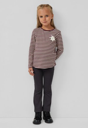 Gestreepte langetermijn top in bordeauxrood en crème, met een bloemaccent, gecombineerd met donker geribbelde broek en zwarte veterschoenen.