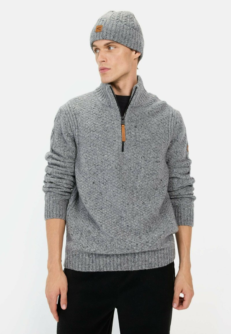 Grijze gebreide trui met een kwart-ritszak en geribbelde manchetten, gecombineerd met een bijpassende kabelgebreide beanie met een leren label.