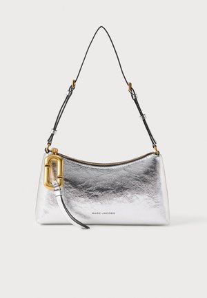 Sac à bandoulière métallisé argenté Marc Jacobs avec sangle noire réglable, fermeture éclair dorée et grande boucle décorative dorée sur fond blanc.