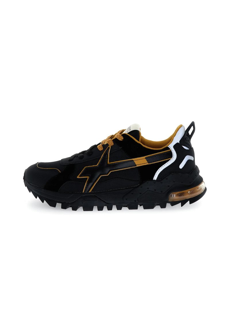 Sneaker atletiche nere con accenti oro e bianchi, caratterizzate da una tomaia testurizzata, suola in gomma spessa e ammortizzazione visibile nel tallone.