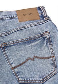 Jeans de mezclilla de tela azul claro, con una etiqueta de cuero de Mustang en la cintura, costuras naranjas y un diseño decorativo en el bolsillo trasero.