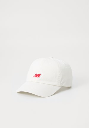 Fehér pamut baseball sapka, ívelt szélekkel és az elején piros hímzett "NB" logóval. Klasszikus dizájn, állítható pánttal.