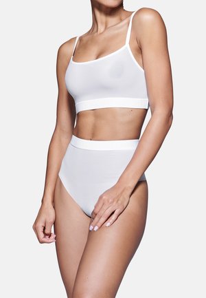 Top corto bianco senza cuciture con spalline sottili e slip a vita alta coordinati. Realizzato in tessuto morbido, presenta una comoda vita elastica.