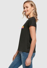Sort t-shirt med korte ærmer, der har farverig "COOL" tekst. Fremstillet af blødt bomuld med en afslappet pasform. Enkel design og rene linjer.