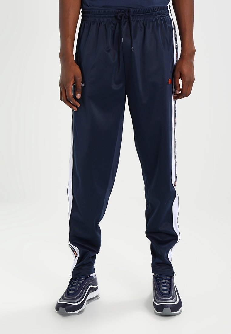 Marinblåa träningsbyxor gjorda av glatt tyg, med vita sidsnoddar och ett elastiskt midjeband med dragsko för justerbar passform.