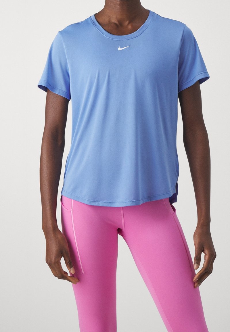 Modrá sportovní tričko Nike s krátkým rukávem, kulatým výstřihem a malým bílým logem. Kombinované s přiléhavými růžovými legínami s bočním švem.